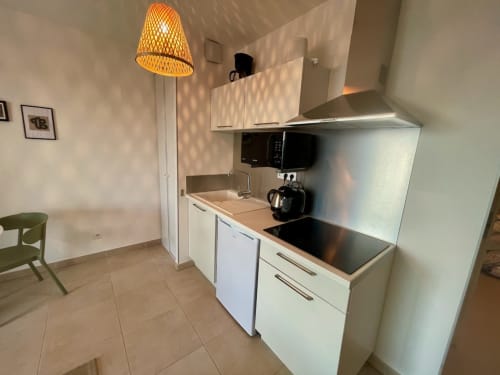 Cuisine moderne avec armoires blanches et lampe suspendue, résidence Marina di Bravone, Linguizzetta
