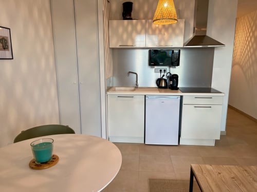 Kitchenette moderne de l'appartement en bord de mer à la Résidence Marina di Bravone, Corse, avec meubles blancs et coin repas
