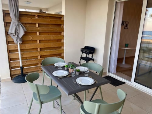 Salle à manger vue mer de l'appartement avec chaises vertes et table noire à la Résidence Marina di Bravone, Linguizzetta