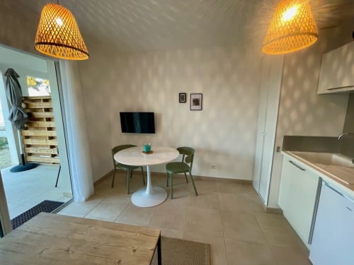 Appartement moderne en bord de mer à la Résidence Marina di Bravone avec coin repas, table ronde, kitchenette et mobilier tissé