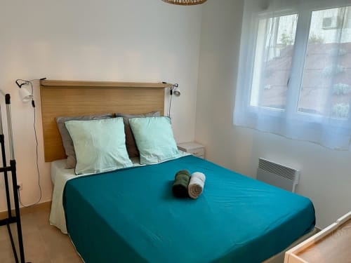 Chambre d'appartement face à la mer à la Résidence Marina di Bravone, avec literie bleu-vert, oreillers menthe et tête de lit en bois