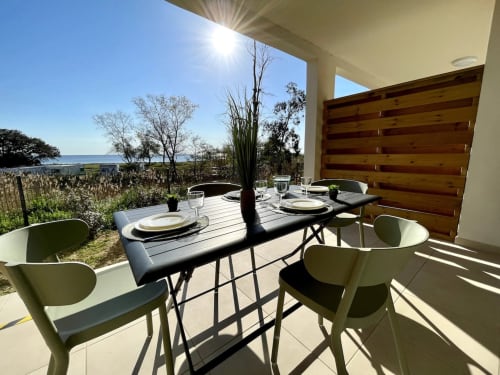 Terrazza di appartamento fronte mare alla Résidence Marina di Bravone con tavolo da pranzo, sedie moderne e vista sul mare