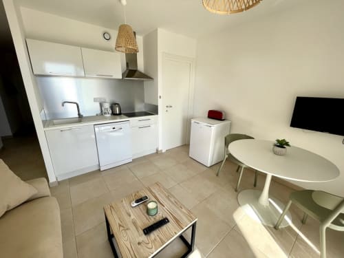 Moderno appartamento T3 a Résidence Marina di Bravone, Linguizzetta. Soggiorno open-plan con cucina bianca, tavolo da pranzo e