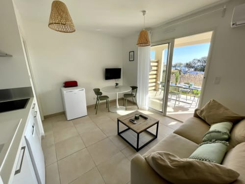 Moderno appartamento a Marina di Bravone con divano beige, angolo cottura, zona pranzo e balcone con vista mare a Linguizzetta