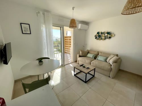 Elegante appartamento T3 a Résidence Marina di Bravone a Linguizzetta con divano beige, zona pranzo e balcone con vista mare
