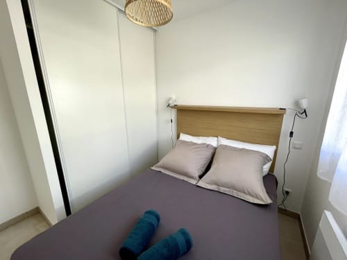 Camera accogliente presso la Résidence Marina di Bravone a Linguizzetta con letto in legno, cuscini beige e moderno armadio bianco