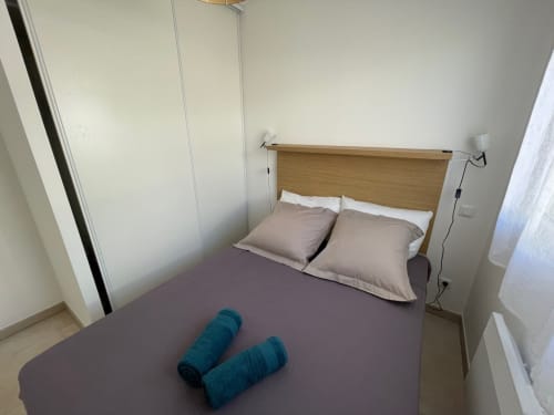 Camera da letto in Résidence Marina di Bravone a Linguizzetta, con letto testata in legno e asciugamani color teal