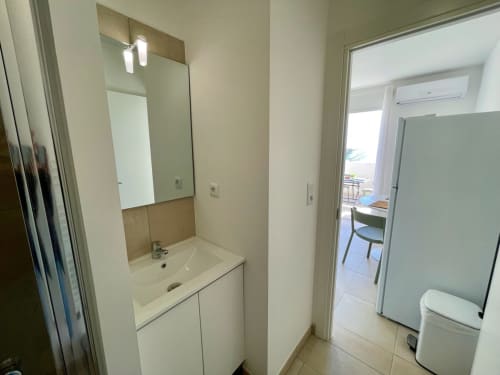 Bagno moderno della Résidence Marina di Bravone a Linguizzetta con lavabo, specchio, illuminazione e water
