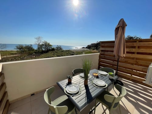 Terrazza fronte mare di Résidence Marina di Bravone con tavolo da pranzo, vista sul mare e schermo in legno