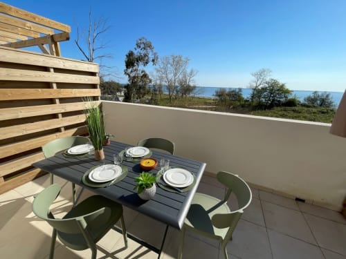 Terrazza vista mare della Résidence Marina di Bravone con tavolo da pranzo, sedie e veduta panoramica sul mare verso Linguizzetta
