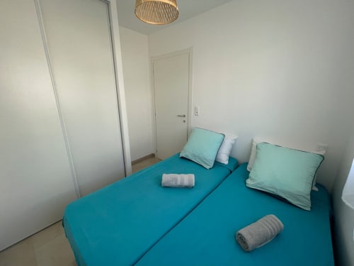 Camera luminosa alla Résidence Marina di Bravone con letto turchese, cuscini menta e arredamento minimalista moderno a Linguizzetta
