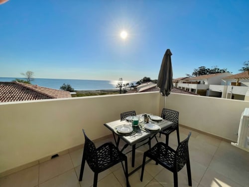 Terrasse panoramique de la Résidence Marina di Bravone avec vue mer, table à dîner et parasol à Linguizzetta