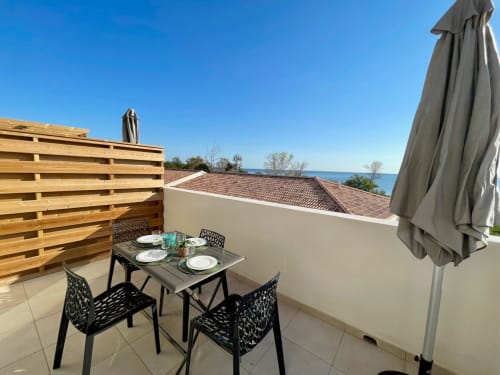 Terrasse bord de mer de la Résidence Marina di Bravone avec table à manger, vue sur la mer et parasol à Linguizzetta