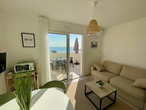 Appartement Marina di Bravone avec canapé beige, terrasse vue mer et mobilier moderne surplombant la côte méditerranéenne