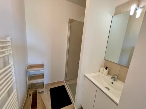 Salle de bain moderne à la Résidence Marina di Bravone avec lavabo, miroir, douche et porte-serviettes