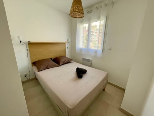 Chambre moderne à la Résidence Marina di Bravone à Linguizzetta avec tête de lit en bois, linge blanc et portes-fenêtres