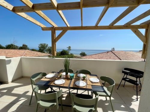 Panoramic sea view terrace at Résidence Marina di Bravone with dining setup and wooden pergola overlooking Mediterranean