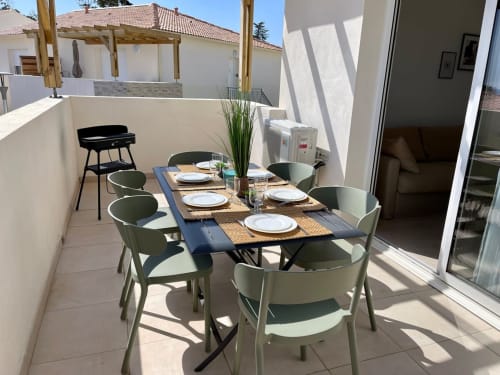 Outdoor terrace at Résidence Marina di Bravone with dining table, green chairs, and sea view in Linguizzetta