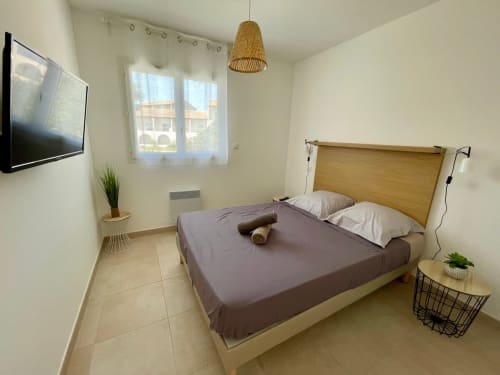 Modern bedroom at Résidence Marina di Bravone, Linguizzetta with wood headboard, TV, and beach views