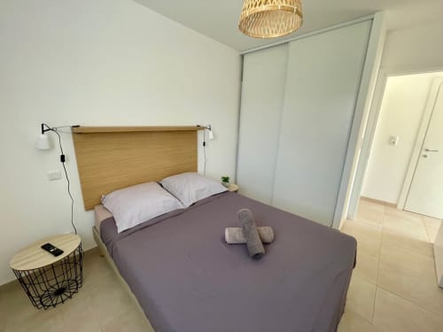 Modern bedroom at Résidence Marina di Bravone, Linguizzetta with queen bed, wooden headboard, and minimalist decor