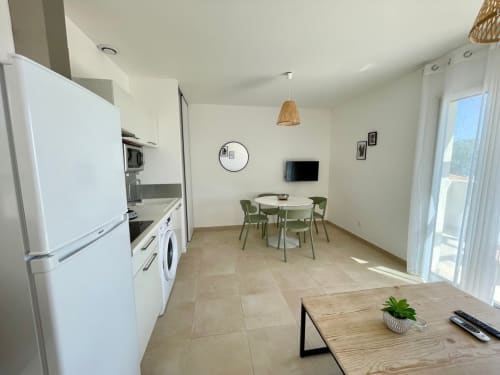 Modern apartment living area at Résidence Marina di Bravone with kitchen, dining table, and sea view access in Linguizzetta
