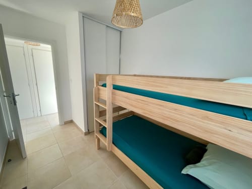 Bright bedroom with wooden bunk beds and teal bedding at Résidence Marina di Bravone, Linguizzetta