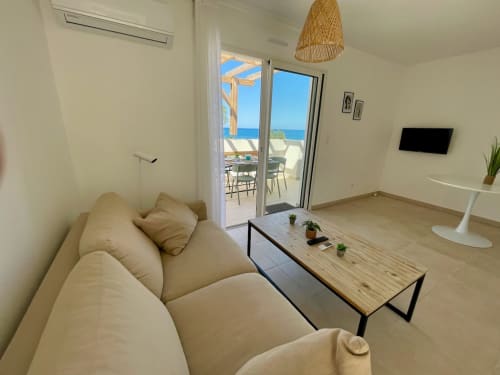 Modern beachfront apartment at Résidence Marina di Bravone with sea views, cream sofa, and terrace access