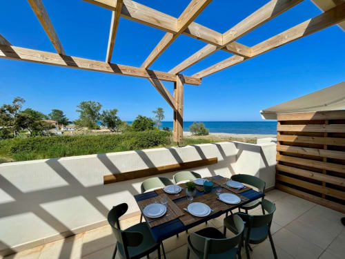 Marina di Bravone terrace with dining table, pergola, and beach view in Linguizzetta