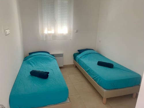 Chambre double de l'appartement 25 à la Résidence Marina di Bravone, Linguizzetta, avec literie turquoise et vue sur mer