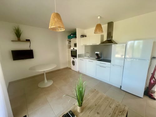 Cuisine moderne et coin repas du T3 à la Résidence Marina di Bravone, Linguizzetta, avec mobilier blanc et luminaires suspendus