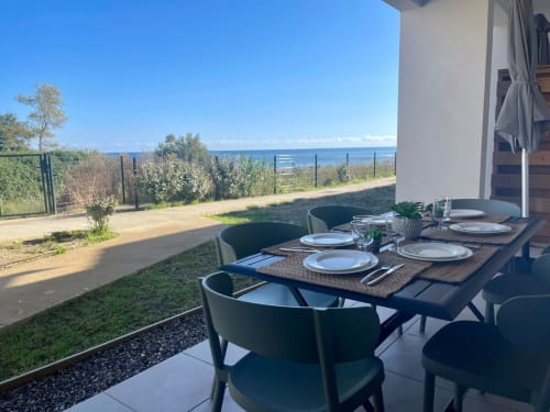 Terrasse de restaurant en plein air à Marina di Bravone avec table dressée, chaises noires et vue sur la mer Méditerranée