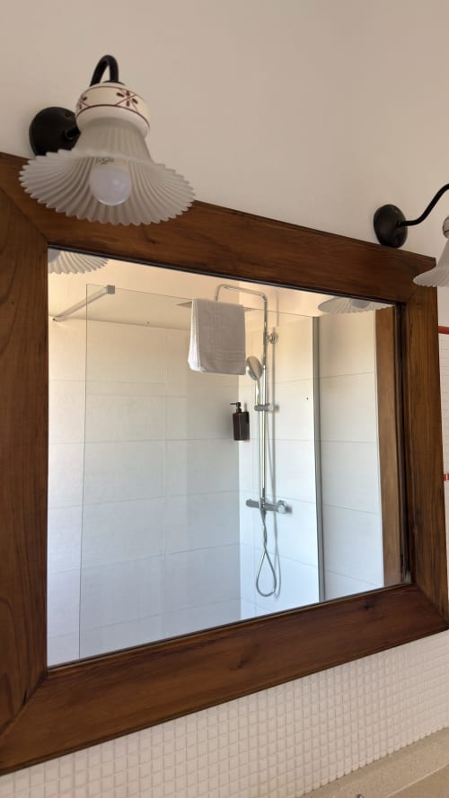 Baño moderno con ducha de cristal, paredes alicatadas en blanco y apliques decorativos de estilo vintage en Apartamentos Rurales