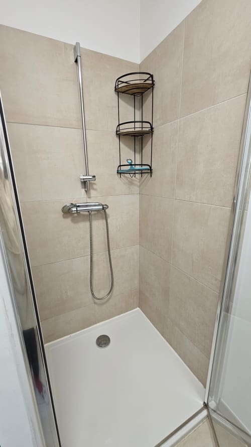 Douche moderne avec carrelage beige, pomme de douche amovible et étagères d'angle à la Résidence Marina di Bravone, Corse