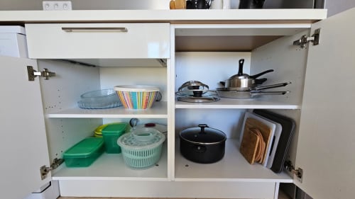 Cuisine Marina di Bravone : placard avec ustensiles de cuisine, vaisselle et boîtes de rangement organisés sur les étagères