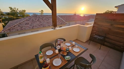 Balcon d'appartement face mer à la Résidence Marina di Bravone avec table de repas surplombant la mer et le coucher de soleil en Corse