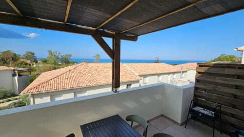 Terrasse en bord de mer à la Résidence Marina di Bravone avec vue sur la mer, mobilier de détente et pergola
