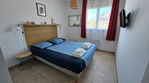 Chambre moderne à la Résidence Marina di Bravone avec literie bleue, tête de lit en bois et vue sur mer à Linguizzetta