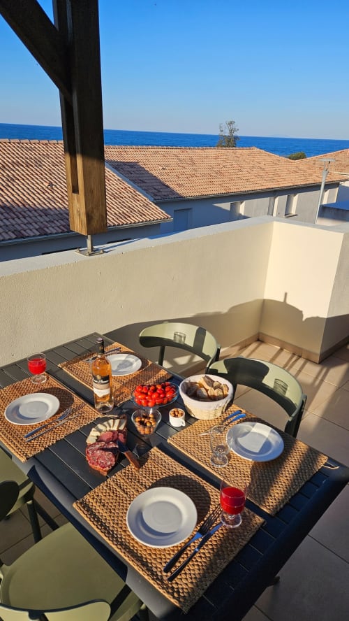 Terrasse d'appartement en bord de mer à la Résidence Marina di Bravone avec vue mer, coin repas et littoral méditerranéen