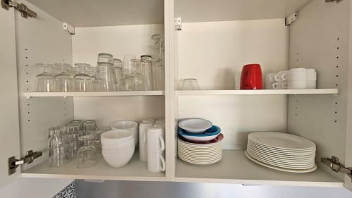 Placard de cuisine ouvert à la Résidence Marina di Bravone montrant une vaisselle bien organisée, des verres et des bols à Linguizzetta