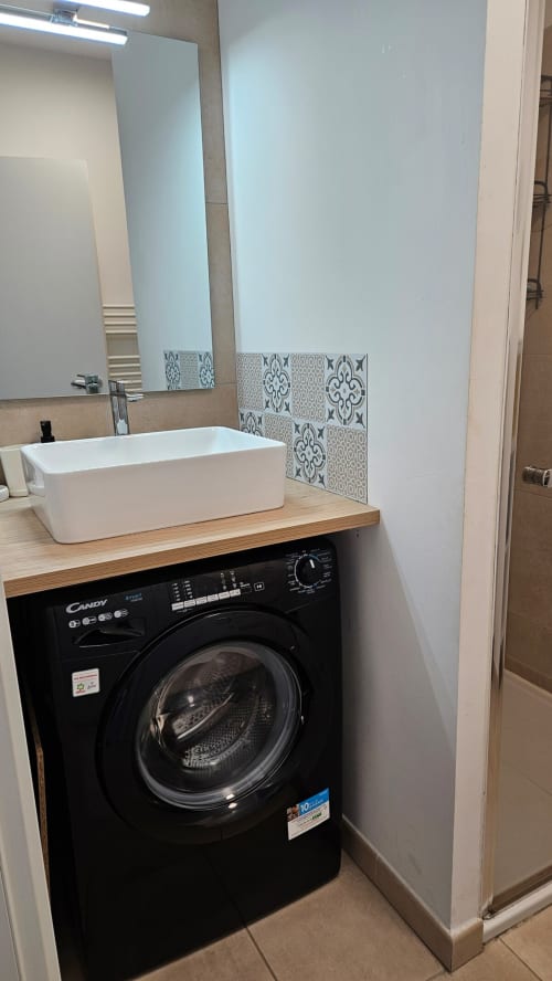 Salle de bains moderne avec lave-linge intégré, vasque blanche et carrelage décoratif à l'hôtel Marina di Bravone