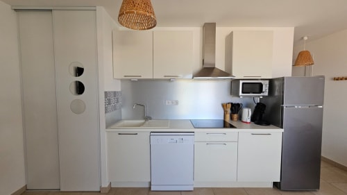 Kitchenette moderne de l'appartement vue mer à Résidence Marina di Bravone, Linguizzetta avec meubles blancs et acier inoxydable