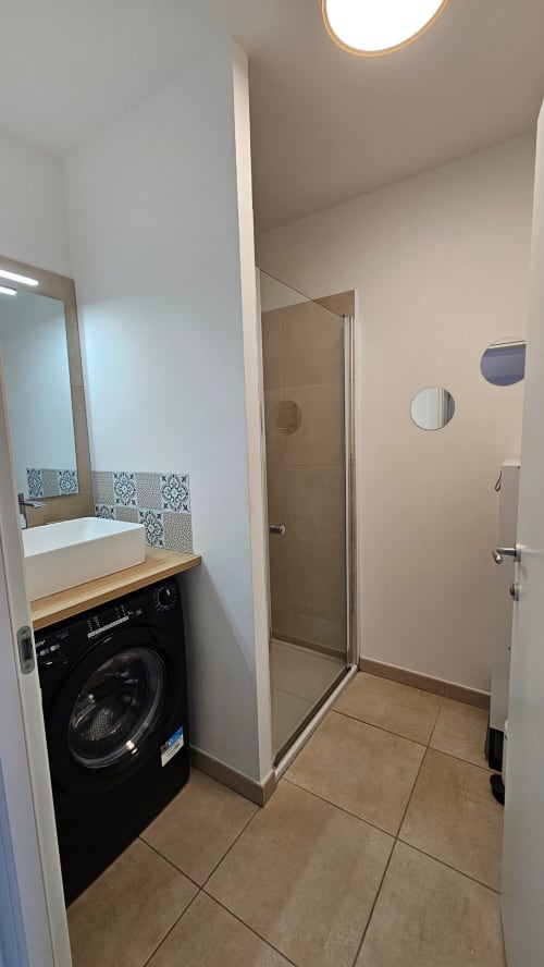 Salle de bain moderne avec lave-linge et douche à la Résidence Marina di Bravone, Linguizzetta