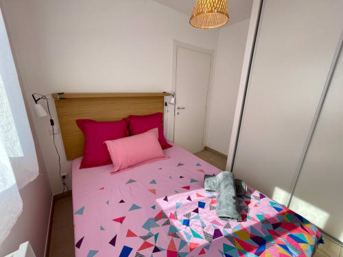 Bright bedroom at Résidence Marina di Bravone with pink bedding, red pillows, and geometric patterns in this Linguizzetta