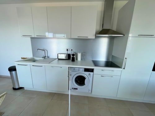 Modern white kitchen with integrated washing machine at Marina di Bravone apartment, Linguizzetta