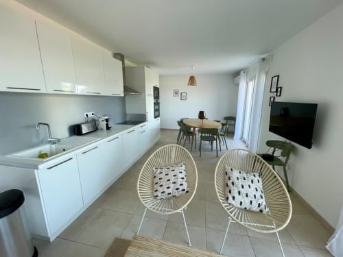 Modern apartment at Résidence Marina di Bravone with open kitchen, dining area, and living space featuring white furniture