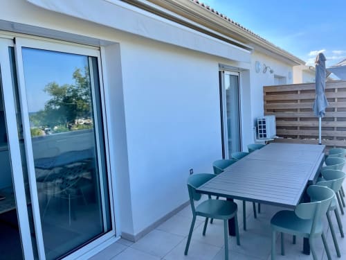 Modern rooftop terrace at Résidence Marina di Bravone with dining table, chairs, and panoramic views in Linguizzetta,