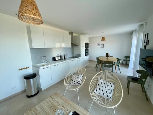 Modern open-plan apartment at Résidence Marina di Bravone with white kitchen, dining area, and comfortable seating