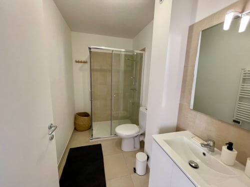 Modern bathroom at Résidence Marina di Bravone with glass shower, toilet, and vanity sink with mirror