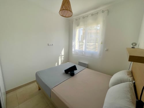 Bright bedroom at Résidence Marina di Bravone in Linguizzetta with double bed, wooden nightstand, and balcony doors