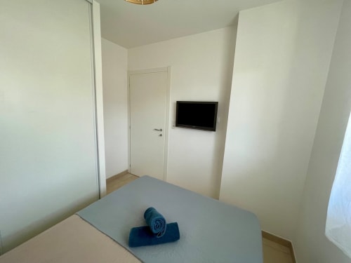 Modern hotel bedroom at Résidence Marina di Bravone with wall-mounted TV, white walls, and minimalist décor